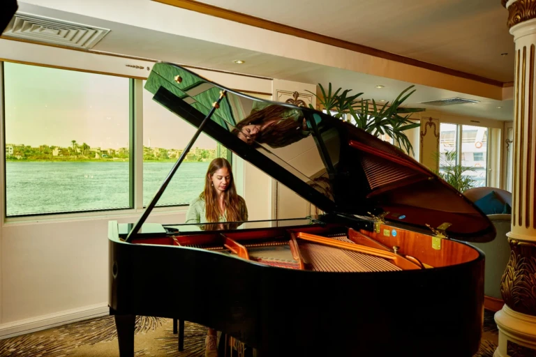 Woman playing a grand piano in the lounge by river windows
