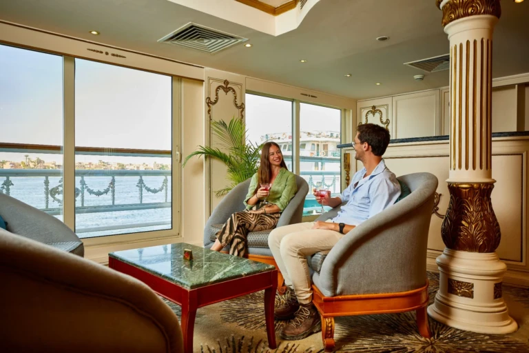 Couple seated in lounge armchairs by Nile view windows