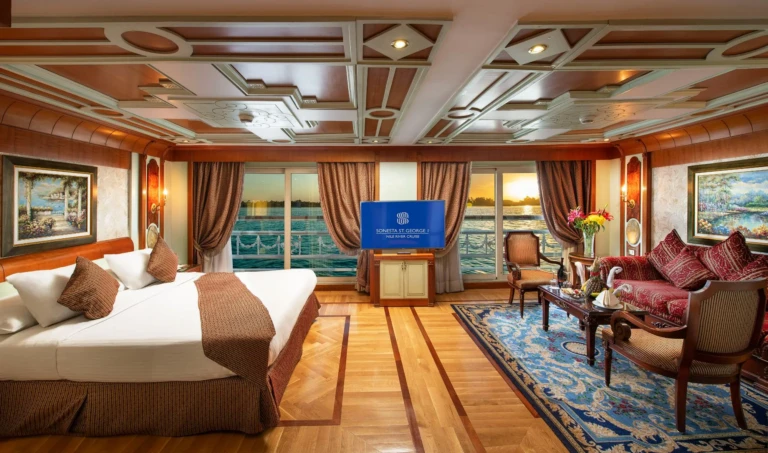 Suite with bed, TV and armchairs facing Nile windows