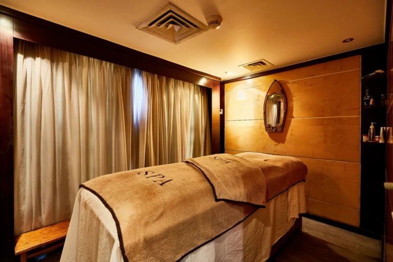 Massage table in spa treatment room beside curtained window