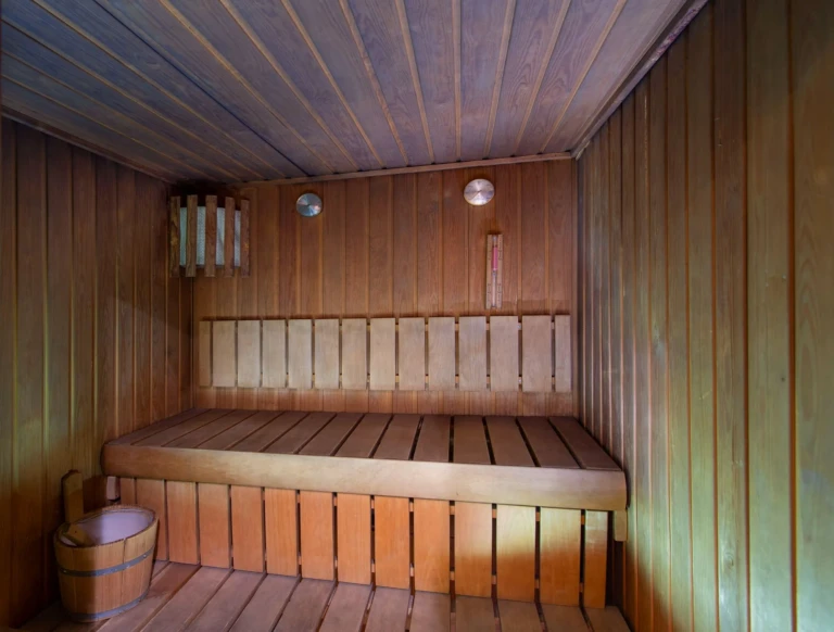 Wooden sauna with slatted benches and a water bucket