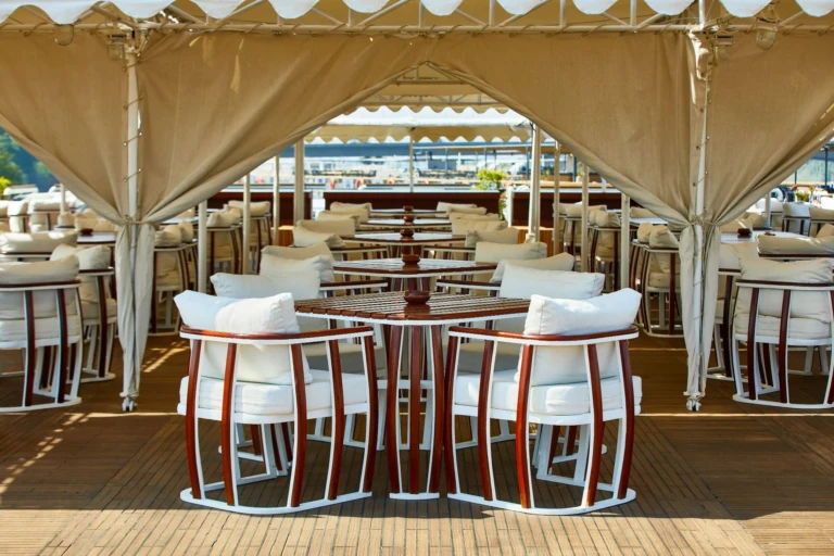 Shaded deck seating with white cushioned chairs under a canopy