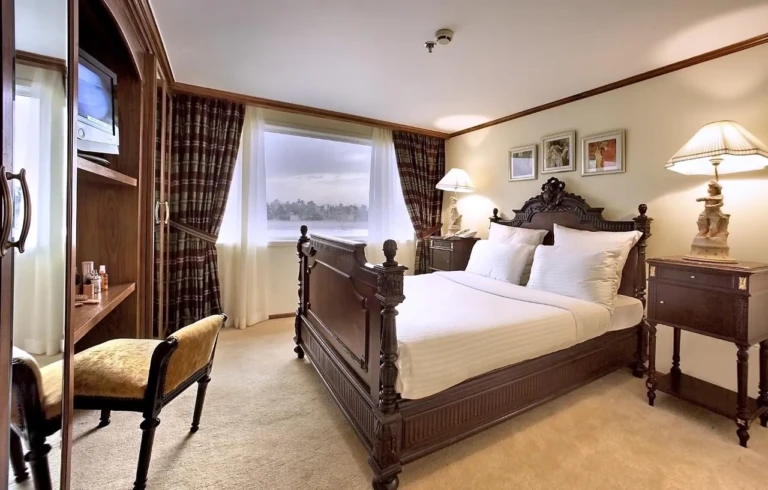 Carved wooden double bed by a Nile window, Sonesta Star Goddess cabin