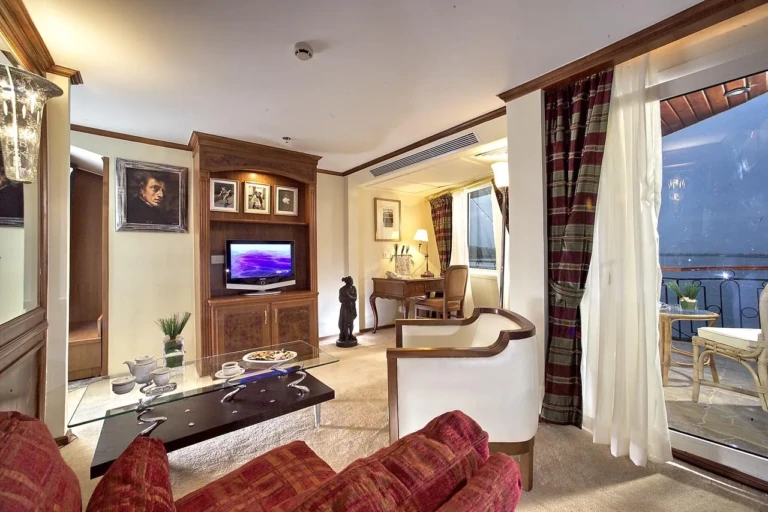 Sonesta Star Goddess suite lounge with red sofa and balcony doors