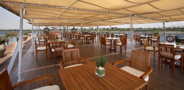 Shaded sun deck with wooden tables and chairs on the Sonesta Star Goddess