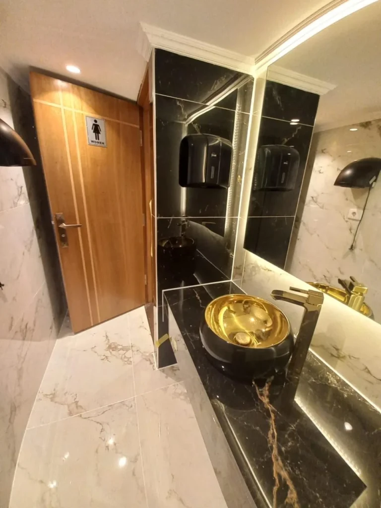 Sonesta Star Goddess restroom with gold basin and wooden door