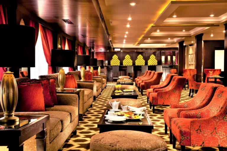 Lounge bar with red armchairs and gold lamps on Steigenberger Legacy