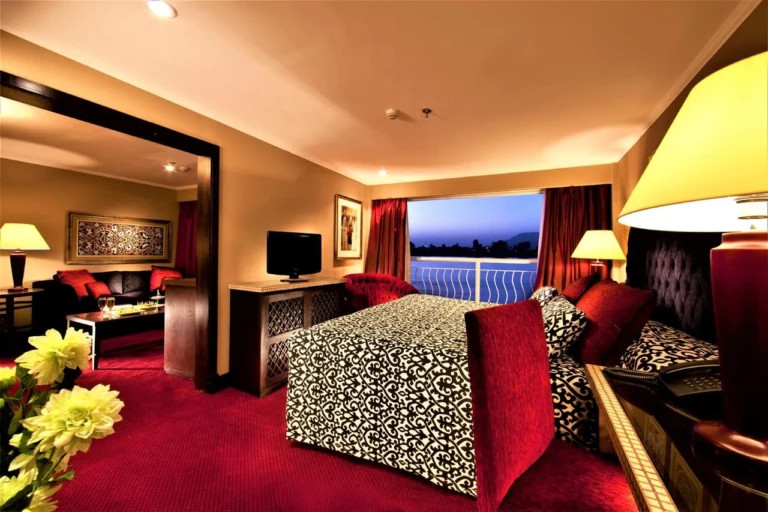 Suite with patterned bed, red carpet and balcony on Steigenberger Legacy