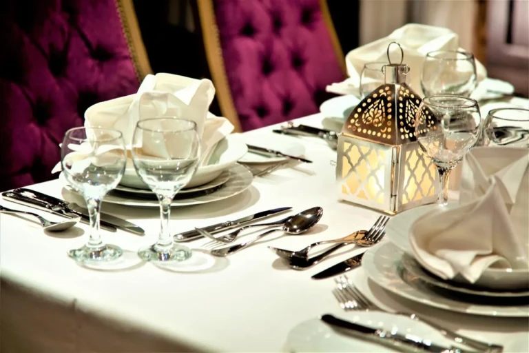 Table setting with lantern and folded napkins before purple chairs