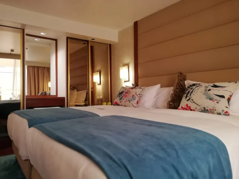 Twin beds with teal throws and mirrored wardrobe on the Sun Goddess