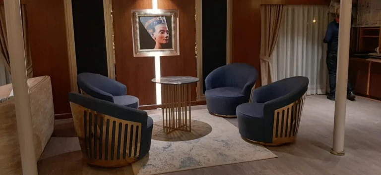 Blue armchairs beneath a Nefertiti portrait on the Sun Goddess