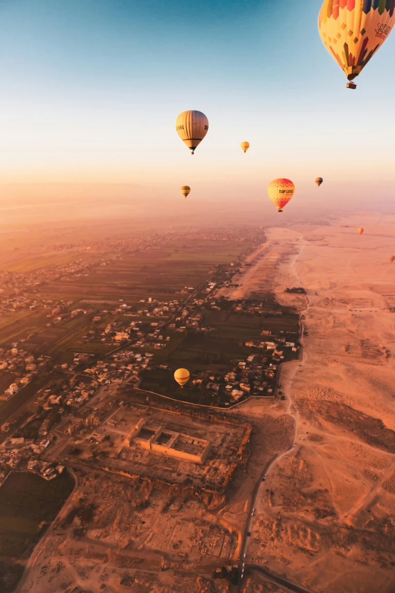Hot air balloons floating above the desert valley at sunrise