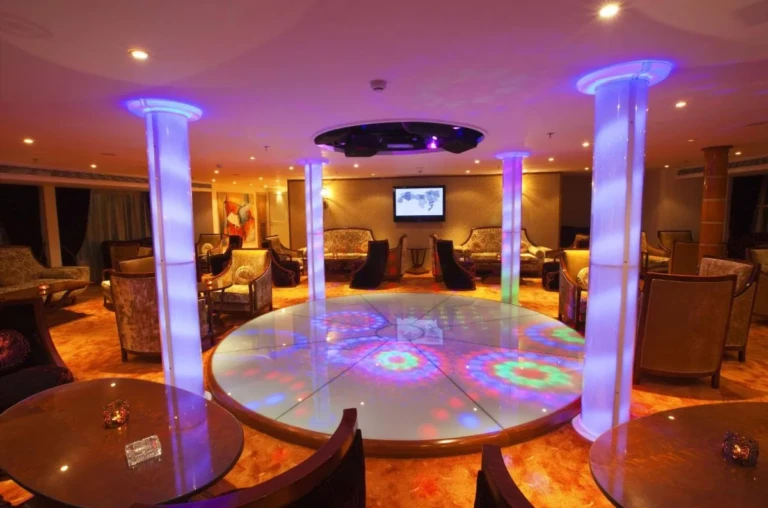 Lounge with illuminated columns and lit dance floor on the Al Hambra