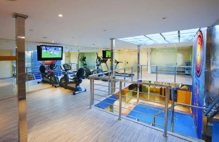 Gym with treadmills and TVs above the atrium on the Al Hambra