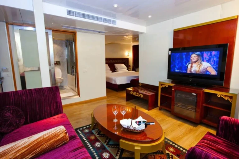 Suite lounge with TV, red sofas and bedroom beyond on the Al Hambra