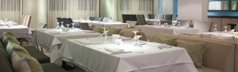 Dining tables with white linen and cushioned benches on the Farida