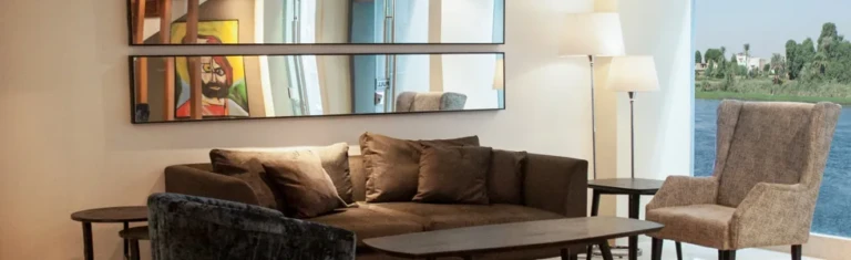 Sofa and armchair beside river windows on the Farida