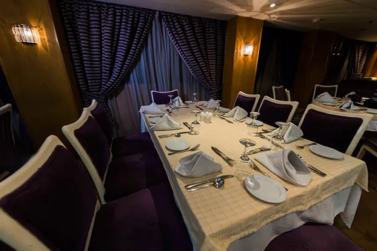 Restaurant table set with folded napkins and purple chairs