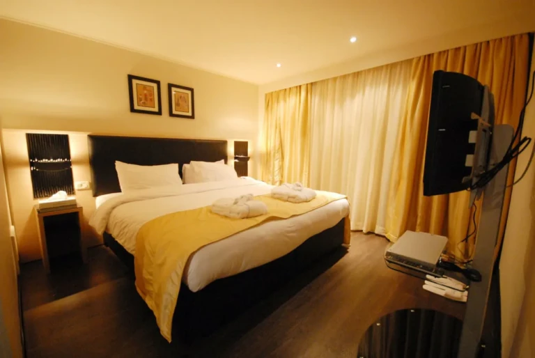Double bed with folded towels and wall-mounted TV