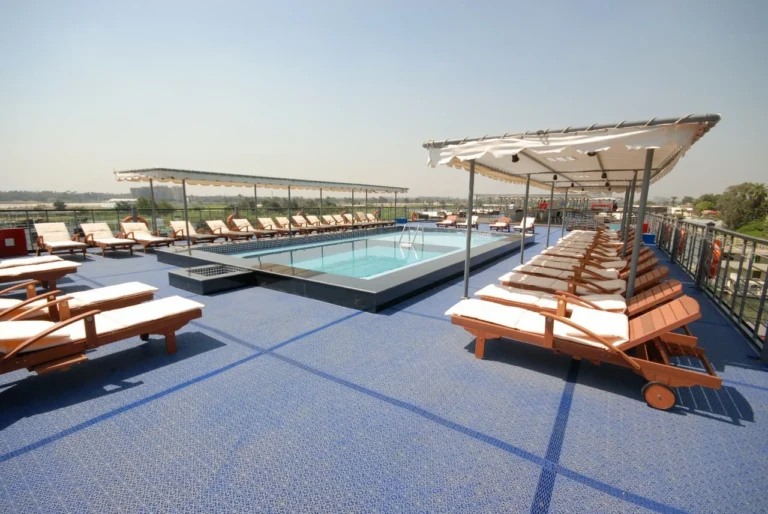 Pool deck with wooden loungers and shade canopies