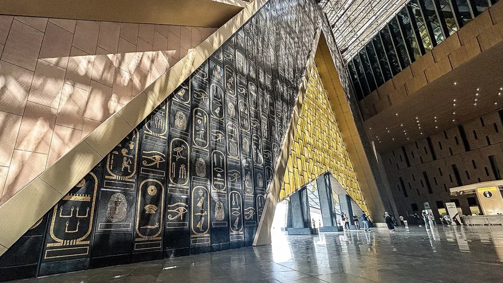 Hieroglyph-covered wall and glass atrium inside the Grand Egyptian Museum