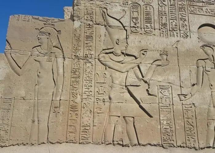 Carved reliefs of gods and a pharaoh on a wall at Kom Ombo Temple
